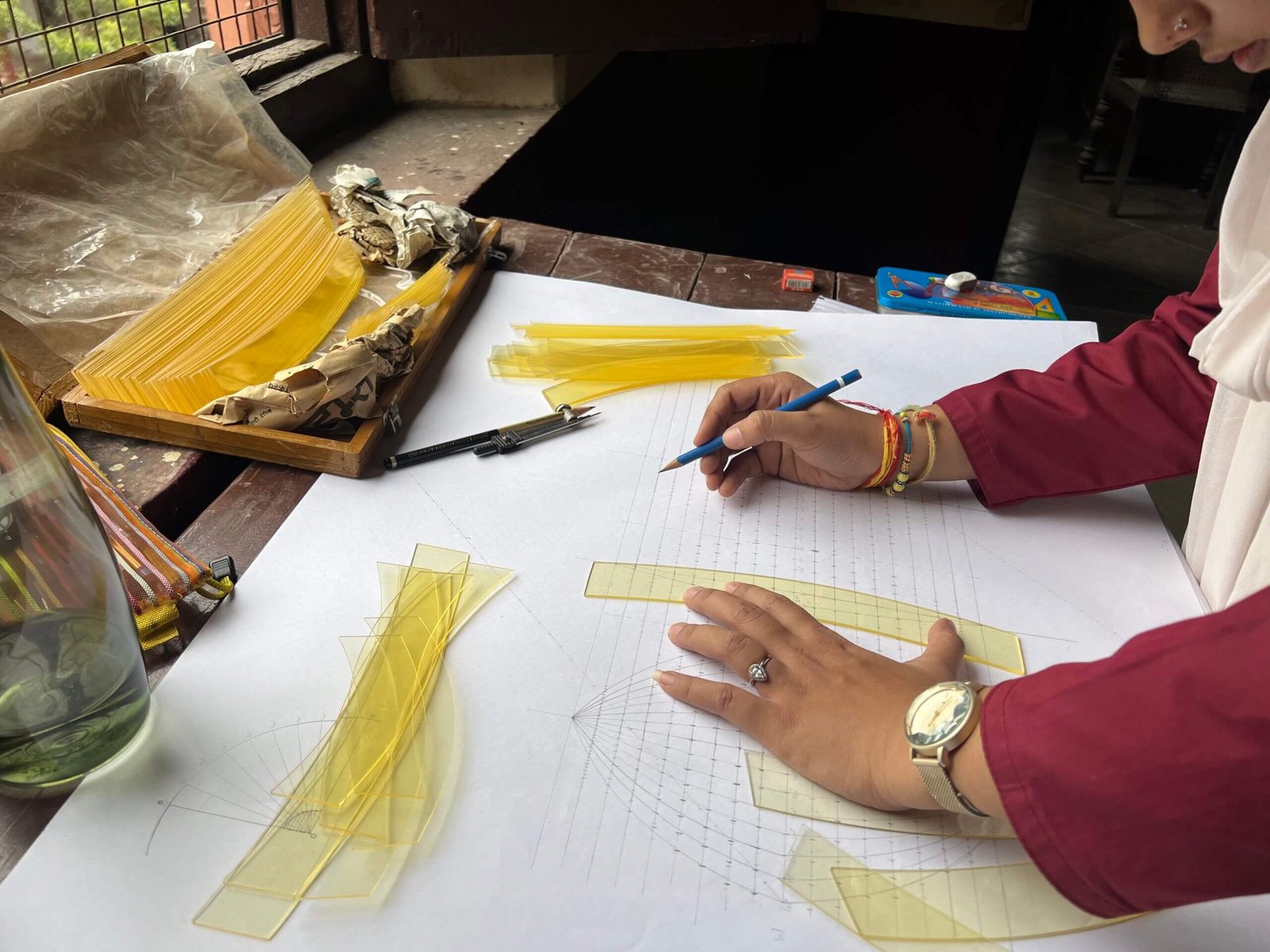 A student carefully drawing curved meridians using a flexible cartographic template