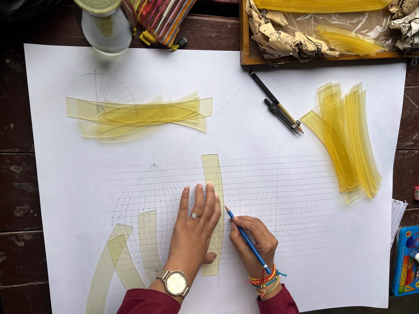 A student using a straight template to draw evenly spaced parallels across the projection