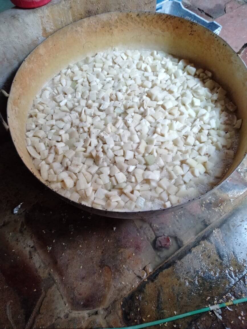 A large metal vessel filled with diced ash-gourd pieces during petha preparation